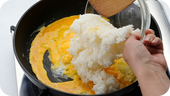 半熟のたまごの上にごはんを加えているところ