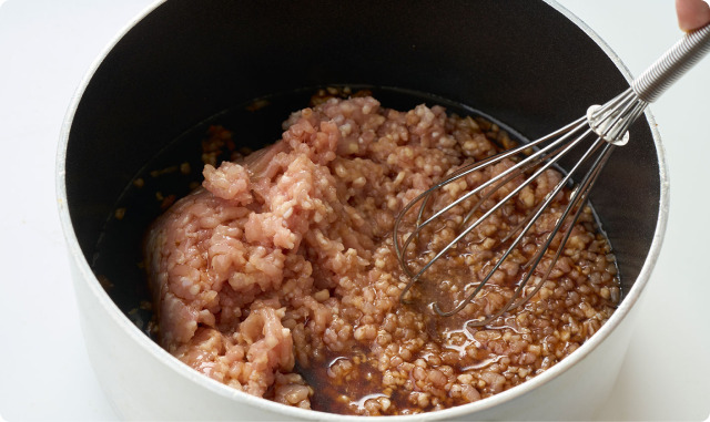 小鍋でひき肉を泡立て器で混ぜながら炒め煮しているところ