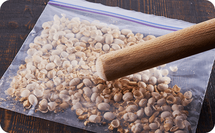 衣用に使う福豆は、保存袋に入れて麺棒で叩いて砕きます。